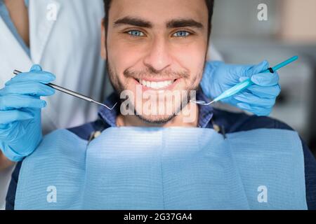 Nahaufnahme eines hübschen jungen Mannes, der seine weißen Zähne zeigt Stockfoto