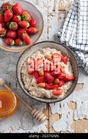 Frühstück Haferflocken mit Erdbeeren und Honig auf Betontisch Hintergrund, Blick von oben. Gesundes Haferflocken, vegetarisches Essen Stockfoto