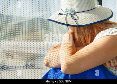Hübsche Frau wartet auf die Abfahrt am Flughafen. Weibliche Reisende sitzt auf dem Boden neben dem Fenster mit Blick auf eine Start- und Landebahn Stockfoto