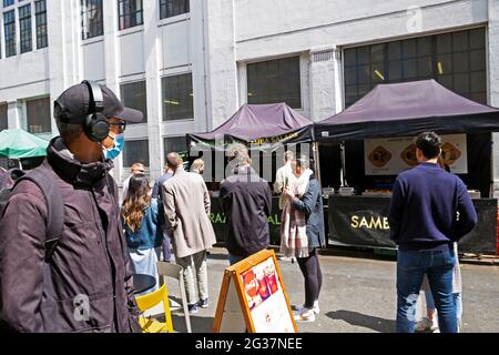 An einem Stand auf dem Londoner Markt der Leather Lane EC1 STEHT man in der Schlange, UM Straßenessen zu essen. KATHY DEWITT Stockfoto