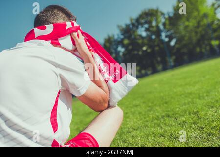 Frustrierter und weinender Fan der polnischen Fußballmannschaft in den Farben Rot und Weiß. Stockfoto