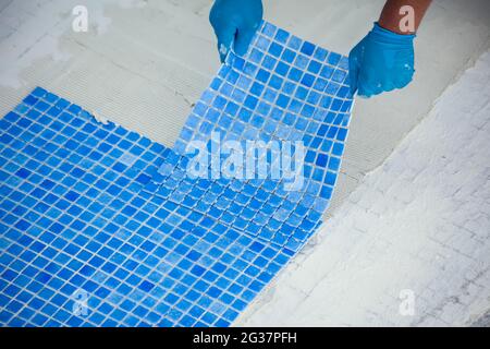 Arbeiter, der Fliesen im Pool legt. Reparaturarbeiten am Pool. Stockfoto