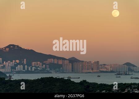 Der Vollmond steigt über Pok Fu Lam, Cyberport und Telegraph Bay auf der westlichen Seite der Insel Hongkong auf Stockfoto