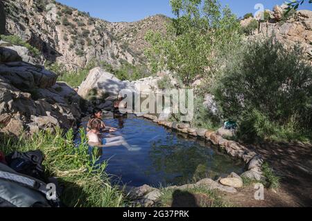 SAN BERNARDINO NATIONAL FOREST, CALIFORNIA, USA - 03. Mai 2021: Badegäste baden in einem natürlichen Thermalbad am Deep Creek im Süden Kaliforniens Stockfoto