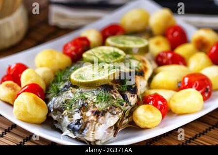 Gebackene Seebrasse mit Babykartoffeln und Kirschtomaten Stockfoto