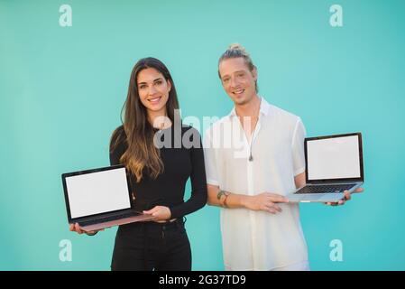 Lächelnde Freunde zeigen Laptops mit leeren Bildschirmen Stockfoto