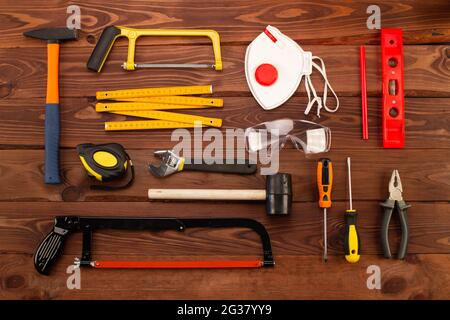 Bauwerkzeuge und Ausrüstung auf schönen braunen Holzplanken Hintergrund. Grundlegende Reparatur-Handwerkzeuge, die jedes Haus haben sollte. Nahaufnahme. Draufsicht Stockfoto