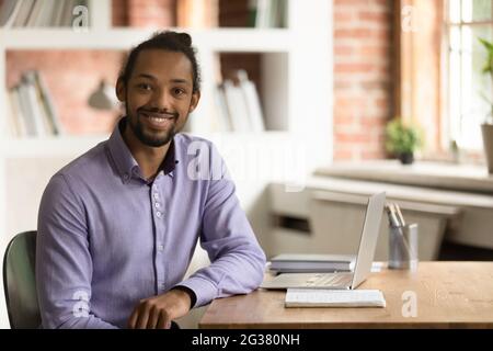 Porträt eines glücklichen jungen afrikanischen männlichen Mitarbeiters, der im Büro posiert. Stockfoto