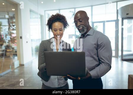 Zwei verschiedene männliche und weibliche Geschäftskollegen, die mit einem Laptop arbeiten und lächeln Stockfoto