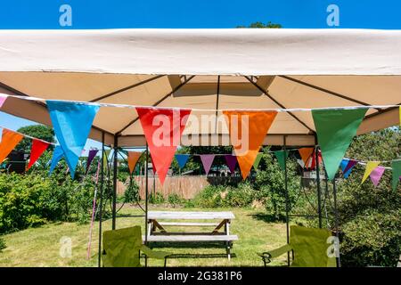 Bunte dreieckige Ammer hängt am Rand eines Pavillons als Dekoration bereit für eine Gartenparty. Stockfoto