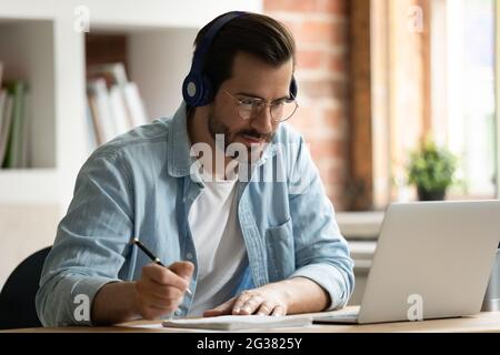 Glücklich fokussierter junger Mann beim Betrachten pädagogischer Vortrag am Computer. Stockfoto