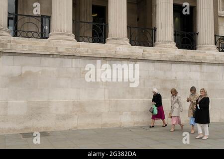 Eine kleine Gruppe von Frauen geht an der wiedereröffneten Nationalgalerie vorbei, während die Lockerung der Coronavirus-Sperre am 25. Mai 2021 in London, Großbritannien, fortgesetzt wird. Museen und Gellerien dürfen nun wieder geöffnet werden, da die Menschen wieder zum normalen Leben zurückkehren. Stockfoto
