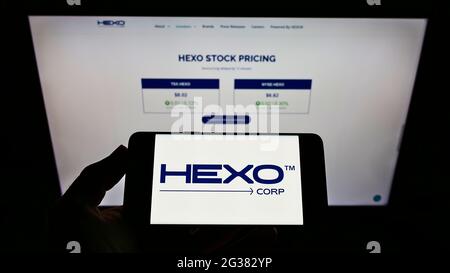 Person, die ein Smartphone mit dem Logo des kanadischen Cannabisunternehmens HEXO Corp auf dem Bildschirm vor der Website hält. Konzentrieren Sie sich auf die Telefonanzeige. Stockfoto