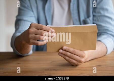 Nahaufnahme des jungen Mannes, der geschäftliche Korrespondenz in Briefumschlägen erhält. Stockfoto