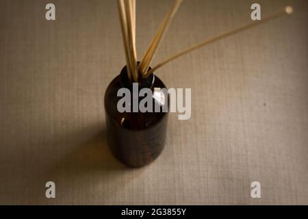 Draufsicht auf eine Diffusorflasche aus dunklem Glas mit natürlichen Schilfrohrstäben Stockfoto