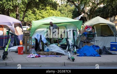 Austin, Texas, USA. Juni 2021. Obdachloser, der in einem Zelt auf einer Straße in der Innenstadt campt, wartet darauf, dass Stadtarbeiter ein großes Obdachloses Protestlager auf der Nordseite des Rathauses in der Innenstadt säubern. Die Polizei verhaftete mehrere Obdachlose, die sich nach mehrwöchigen Warnungen und Hilfsangeboten weigerten, zusammenzuarbeiten. Austin hat zu wenige Notbetten für die Anzahl der Menschen, die auf der Straße leben. Quelle: Bob Daemmrich/Alamy Live News Stockfoto