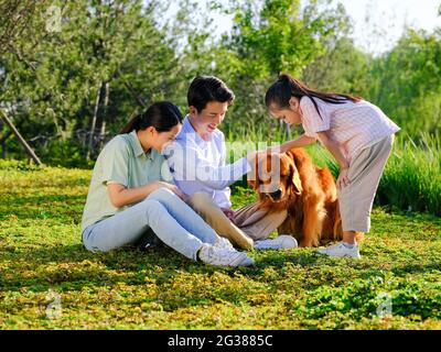 Glückliche Familie von drei und Hund spielen im Park qualitativ hochwertige Foto Stockfoto