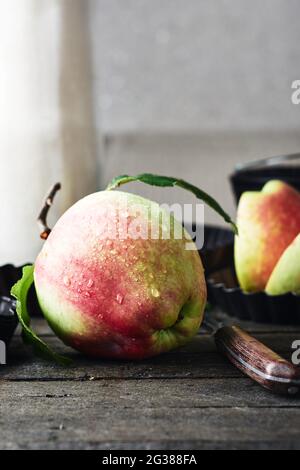 Roter Apfel mit Wassertropfen auf einem hölzernen Küchentisch. Stockfoto