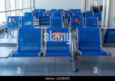 Leere Stühle mit eingeschränktem No-Sitting-Schild im Flughafengebäude, Passagiermangel während der globalen Krise und Krankheiten. Leere Abflughalle A Stockfoto