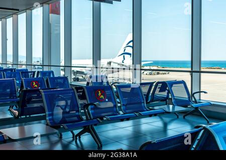 Leere Stühle mit eingeschränktem No-Sitting-Schild im Flughafengebäude, Passagiermangel während der globalen Krise und Krankheiten. Leere Abflughalle A Stockfoto