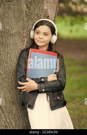 Mädchen hören Audio tragen Lehrbücher entspannend Park Hintergrund, Bibliothek Wiedergabeliste Konzept Stockfoto