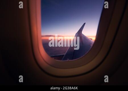 Wunderschöne Aussicht aus dem Flugzeugfenster während des Fluges bei farbenprächtiger Sonnenuntergänge. Stockfoto