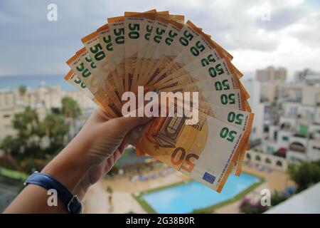 Serie von neuen 50-Euro-Banknoten in weiblicher Hand in Nahaufnahme von Schwimmbecken, Gebäuden, realem Osten, Meer am Horizont, Investitionen, Finanzen, Wirtschaft. Stockfoto