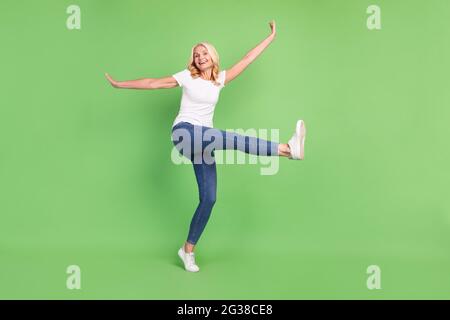 In voller Länge Körpergröße Foto überglücklich ältere Frau in lässigem Outfit lächelnd isoliert pastellgrün Hintergrund Stockfoto