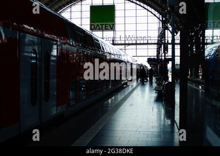 FRANKFUR, DEUTSCHLAND - 10. Jun 2021: Silhouette eines Zuges und Fahrgäste auf dem Bahnsteig am Frankfurter Hauptbahnhof. Hintergrundbeleuchtung und Reflexion. Stockfoto