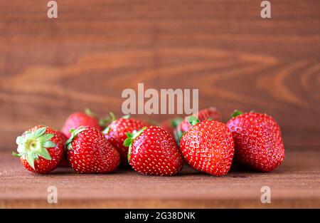 Frische Sommererdbeere auf Holztisch, rustikales Stillleben, Ernte der roten saftigen Erdbeere. Platz für Text. Stockfoto