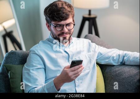Während einer Arbeitspause zu Hause nahm ein bärtiger Mitarbeiter das Telefon auf und wählt eine Nummer. Stockfoto