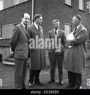 1960s, historisch, William Hamilton, Abgeordneter für West Fife - rechts in Regenmantel und mit Papieren - mit lokalen männlichen Ratsmitgliedern, die vor einem Wohnblock der Stadtverwaltung der frühen 60er Jahre standen, Fife, Schottland, Großbritannien. Stockfoto