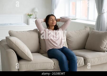 Friedliche, ruhige afroamerikanische Frau, die sich auf der Couch ausruht Stockfoto