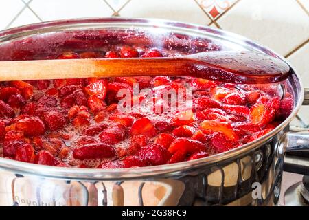 Erdbeermarmelade zu Hause machen - Holzlöffel am Rand des Edelstahltopfes. Schritt 4 von 4. Stockfoto