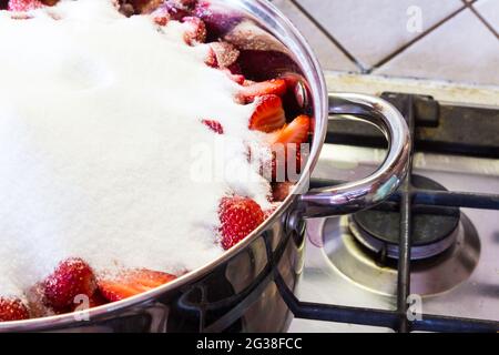 Erdbeermarmelade zu Hause machen - Haufen Erythritol auf Früchten im Edelstahltopf auf Herd. Schritt 3 von 4. Stockfoto