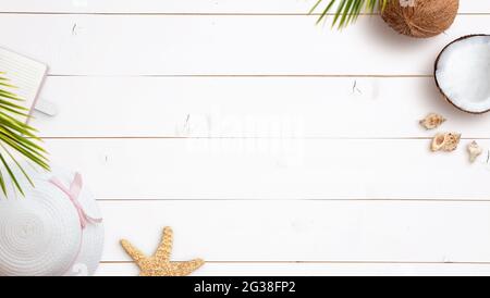 Sommerreise Hintergrundkomposition mit Frauenhut, Notizbuch, Seesternen, Kokosnuss und Muscheln auf weißem Holztisch. Draufsicht, flach liegend Stockfoto