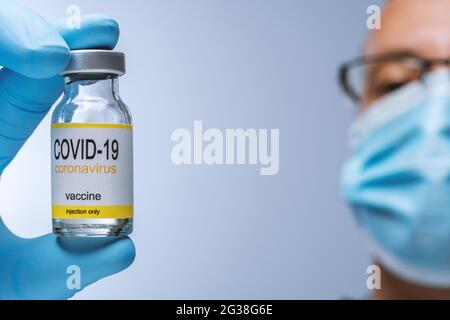 Arzt in blauen Latexhandschuhen hält Glasfläschchen mit Medizin. Impfung, Immunisierung, Behandlung der Infektion mit dem Covid 19 Corona Virus. Gesundheitswesen Und Stockfoto