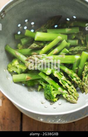 Gedünsteter Brokkoli und grüner Spargel in Sieb Stockfoto