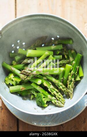 Gedünsteter Brokkoli und grüner Spargel in Sieb Stockfoto