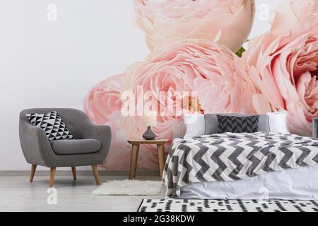 Stilvolles Interieur des Schlafzimmers mit schönen Rosenblumen an der Wand Stockfoto