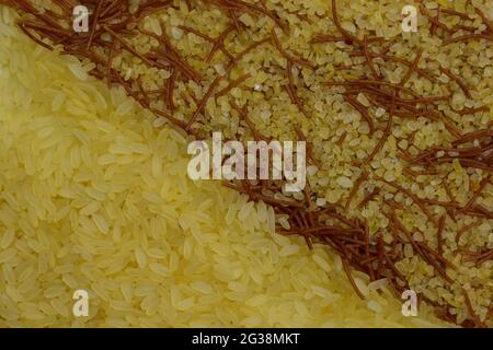 Reis und Couscous mit Vermicelli. Der ganze Rahmen ist schräg in zwei Hälften geteilt, zur Hälfte mit Reis bedeckt und zur Hälfte mit Reis mit feinen braunen Nudeln Stockfoto