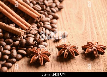 Viele Körner von Kaffee, Anise und Zimt liegen auf einer braunen Holzoberfläche Stockfoto