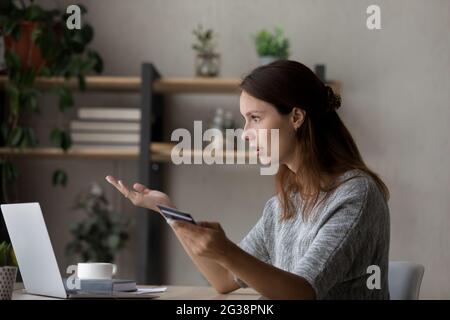 Seitenansicht schockiert unglückliche Frau, die Probleme mit Kreditkarte hatte Stockfoto