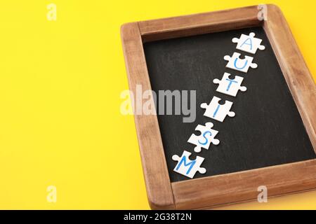 Wort-AUTISMUS aus Puzzles und Kreidetafel auf farbigem Hintergrund Stockfoto