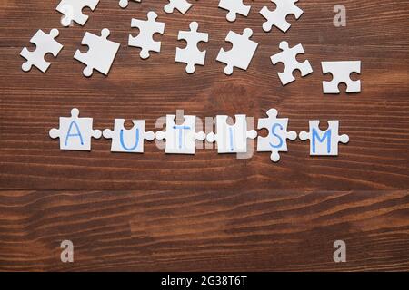 Wort-AUTISMUS aus Puzzles auf dunklem Holzhintergrund Stockfoto