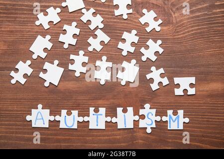 Wort-AUTISMUS aus Puzzles auf dunklem Holzhintergrund Stockfoto