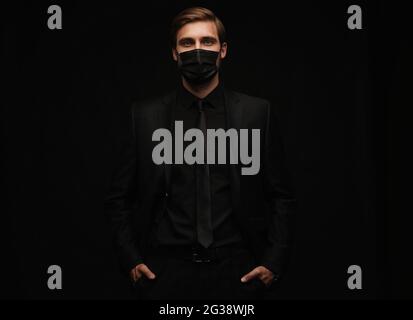 Business Concept - Portrait schöner Geschäftsmann in schützende Gesichtsmaske auf schwarzem Hintergrund Stockfoto