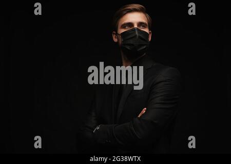 Business Concept - Portrait schöner Geschäftsmann in schützende Gesichtsmaske auf schwarzem Hintergrund Stockfoto