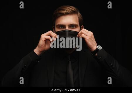 Business Concept - Portrait schöner Geschäftsmann in schützende Gesichtsmaske auf schwarzem Hintergrund Stockfoto