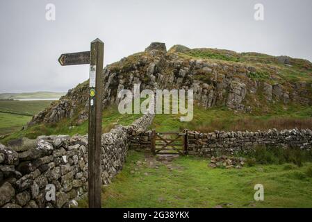 Wegweiser am Hadrian's Wall Path, wo der Pennine Way National Trail die Linie der ehemaligen römischen Grenzmauer überquert. Der Hadrian's Wall Path verläuft entlang des gesamten UNESCO-Weltkulturerbes und ist einer der beliebtesten Wanderwege in England. Stockfoto